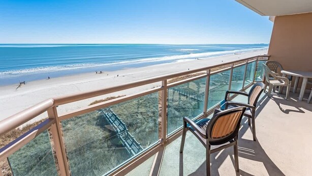 Ein Balkon mit freiem Blick auf den Strand und einer Glasbrücke.