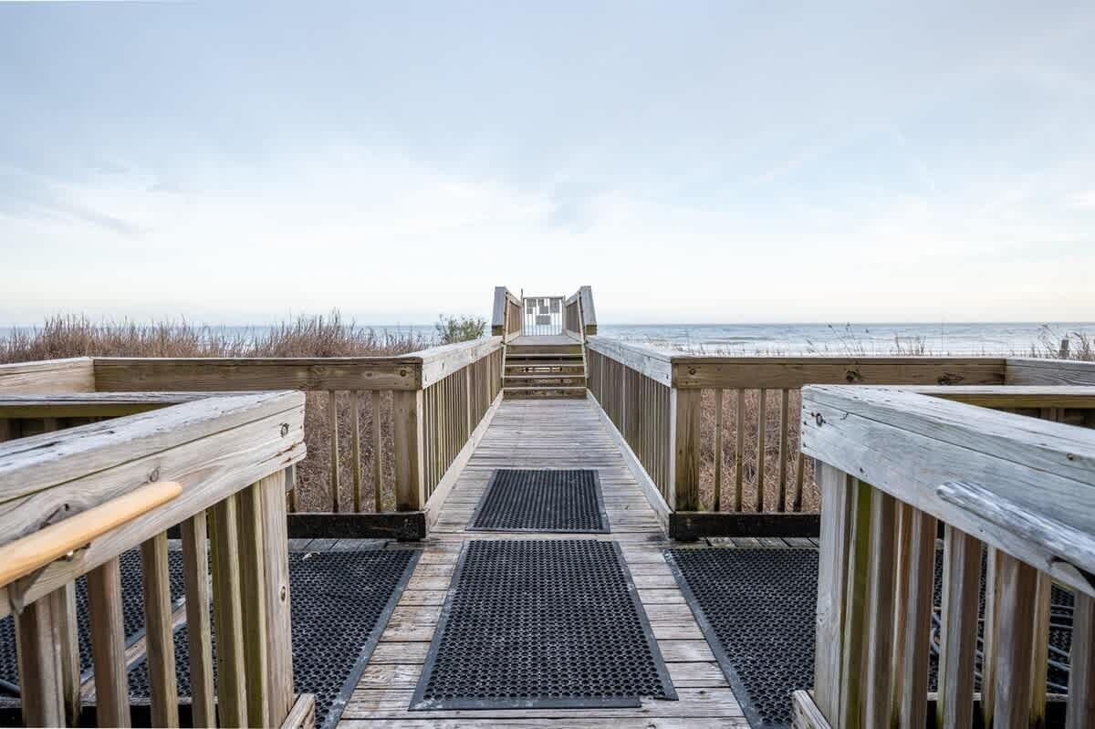 En träpromenad som leder till en strand med fri utsikt över havet.