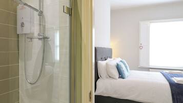 Un baño moderno con cabina de ducha de vidrio, inodoro y lavamanos blancos.