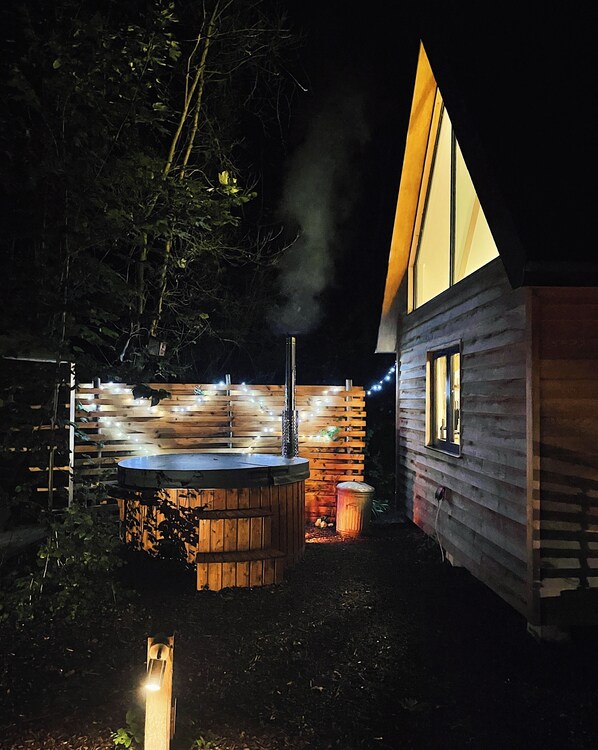 A wooden cabin with a hot tub and a smoke stack.