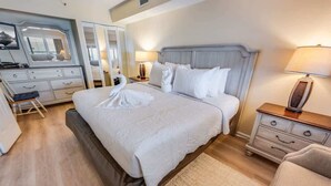 Un dormitorio ordenado con cama, mesitas de noche, cómoda y espejo.