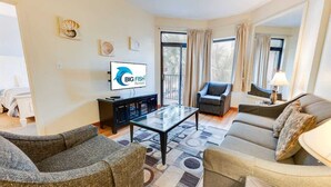 A living room with a television, sofa, and armchair. - Contemporary 2BR Beach Colony Resort, Pools, View (Myrtle Beach)