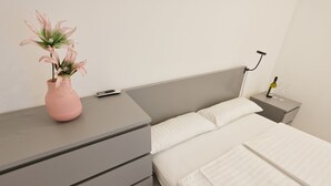 A bedroom with a bed, bedside table, nightstand, and a vase with flowers. - Accommodation " Ana-Marija " (Vodice)