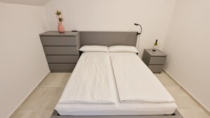A modern bedroom with a bed, bedside tables, a nightstand, a vase with flowers, and a bottle of wine. - Accommodation " Ana-Marija " (Vodice)