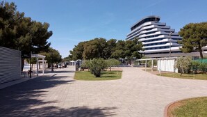 A modern building with a curved facade, a paved walkway, and surrounding greenery. - Apartment "Marko" (Vodice)