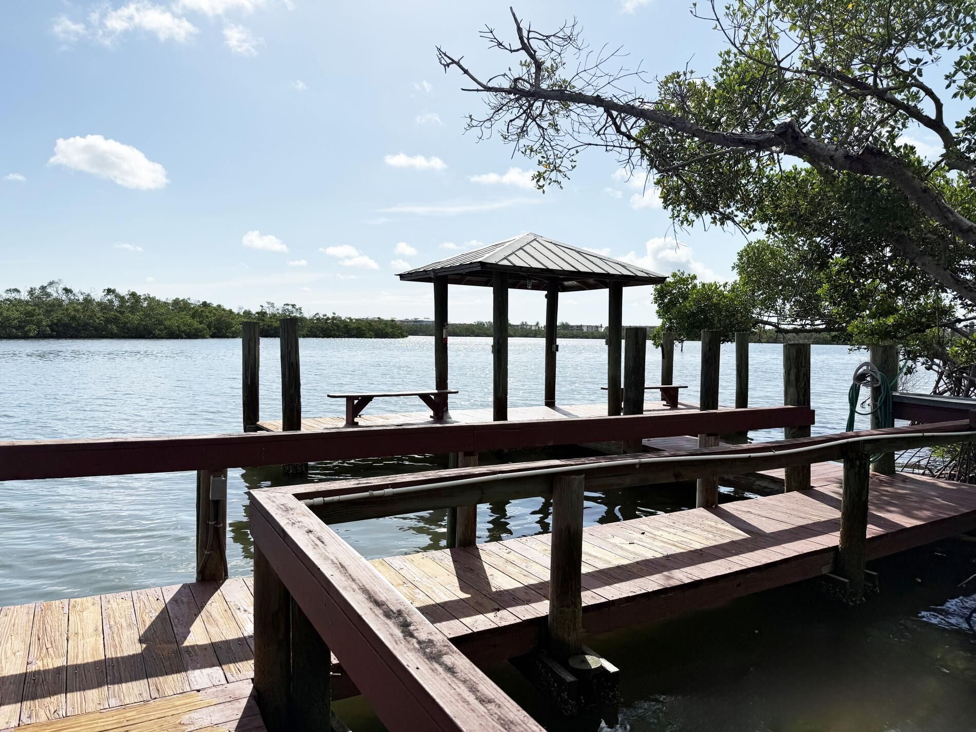 Un muelle de madera con un pabellón y una mesa de picnic, con vista a aguas tranquilas.