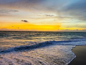 Ein Strand mit Wellen und einem Sonnenuntergang.
