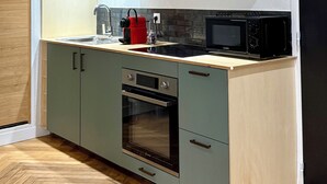 A modern kitchen with light wood cabinets, a built-in oven, and a microwave. - Id-home Le Saint Nicolas (Nantes)