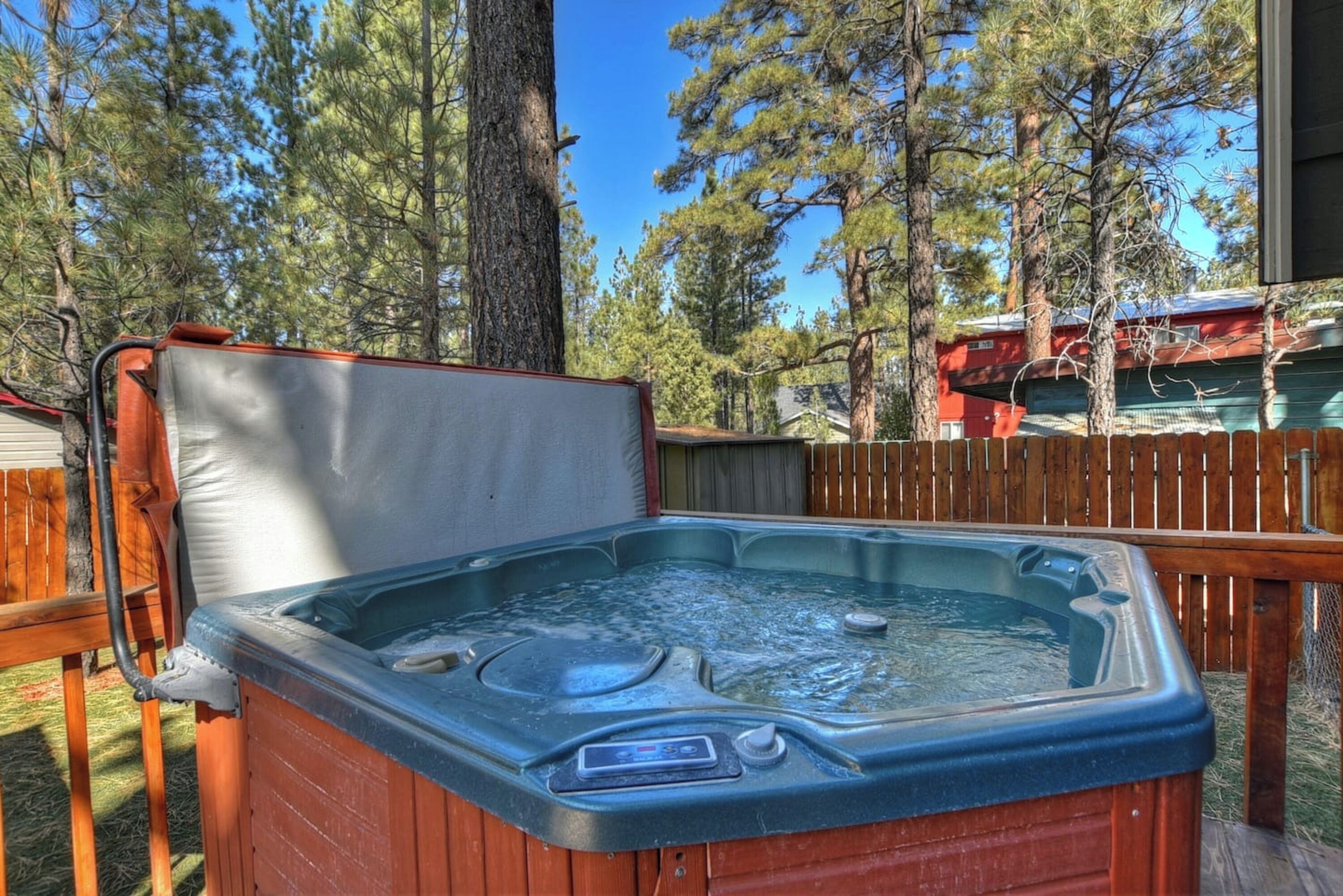 A hot tub outdoors with a wooden deck and trees in the background.