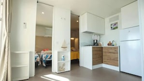 A compact, modern room with a kitchenette, a bed, and a small seating area.