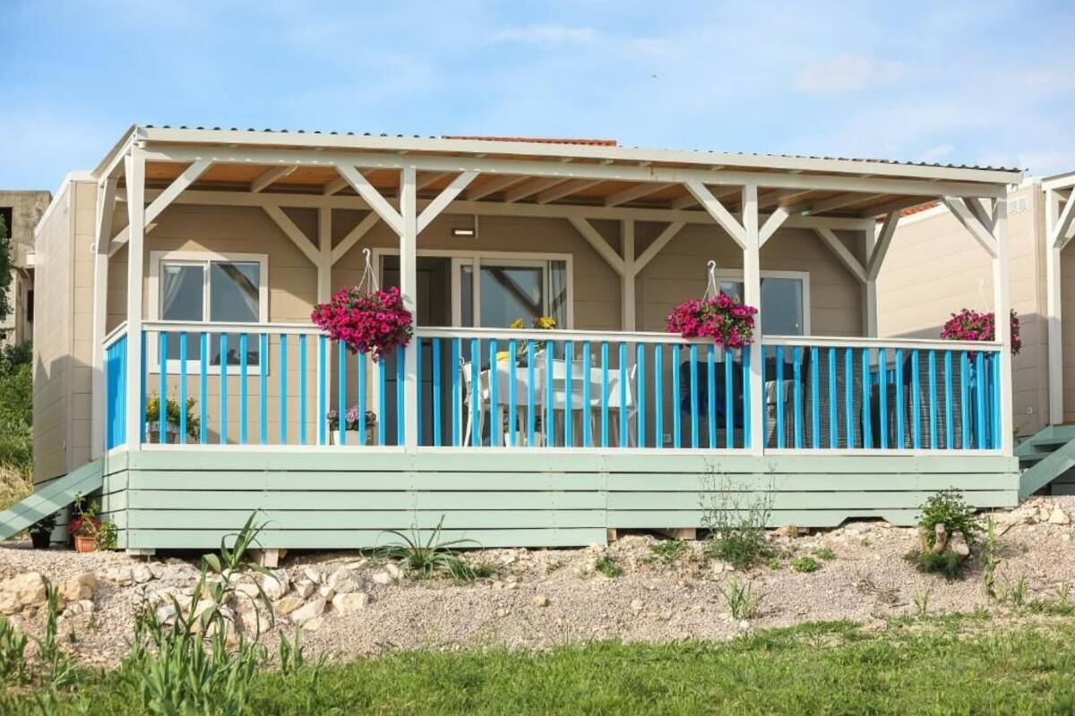 Un edificio a due piani con un balcone, un portico coperto e un piccolo spazio esterno con sedute.