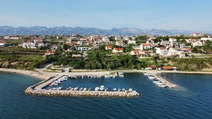 A coastal town with a marina, houses, and mountains in the background.
