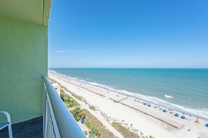 Een balkon met uitzicht op een strand, een heldere lucht en de oceaan.