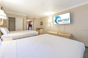 Een hotelkamer met twee bedden, een aan de muur bevestigde televisie, een bureau en een kledingkast.