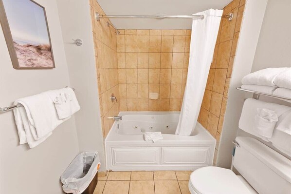 A bathroom with a bathtub, toilet, and a shower curtain.