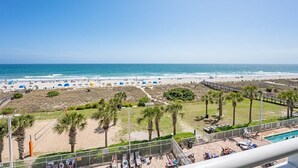 A beach view from a balcony with a pool, palm trees, and beach umbrellas. - Dunes Village 3BR - Waterpark - Direct Oceanfront (Myrtle Beach)
