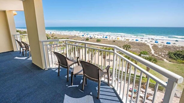A balcony with a view of the beach, featuring chairs and a railing. - Dunes Village 3BR - Waterpark - Direct Oceanfront (Myrtle Beach)