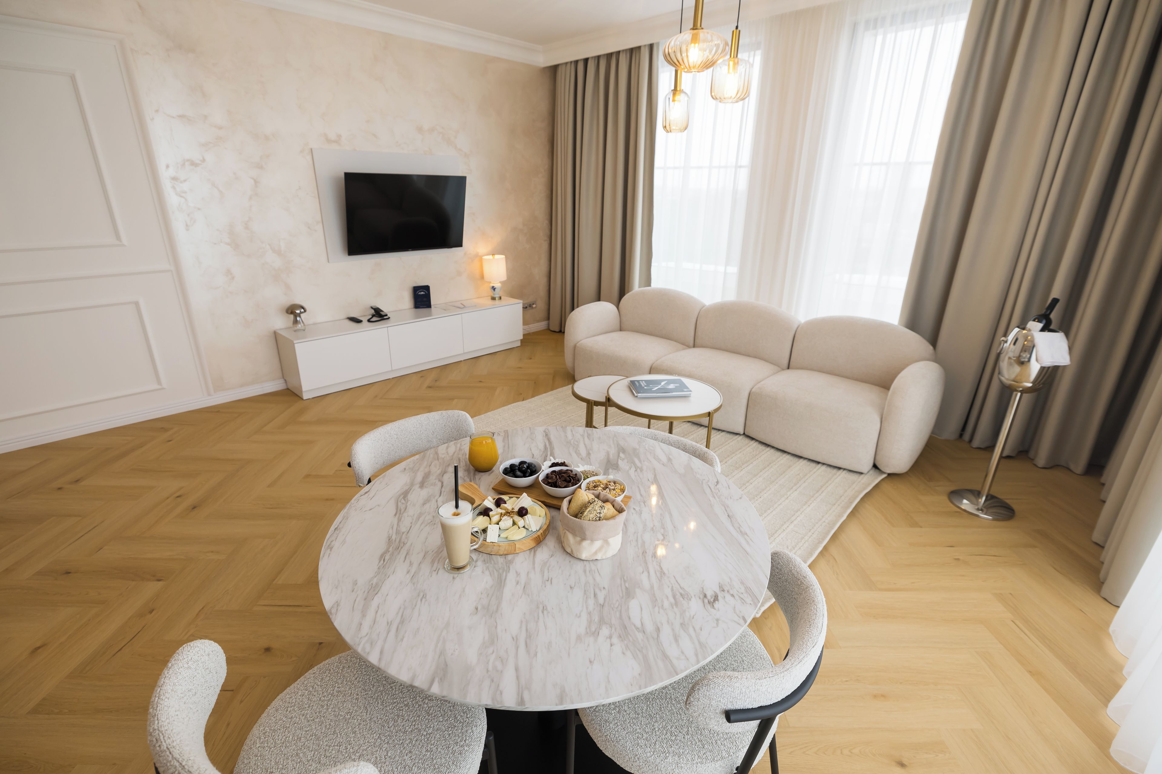 A modern living room with a marble dining table, a sofa, and a television mounted on the wall.