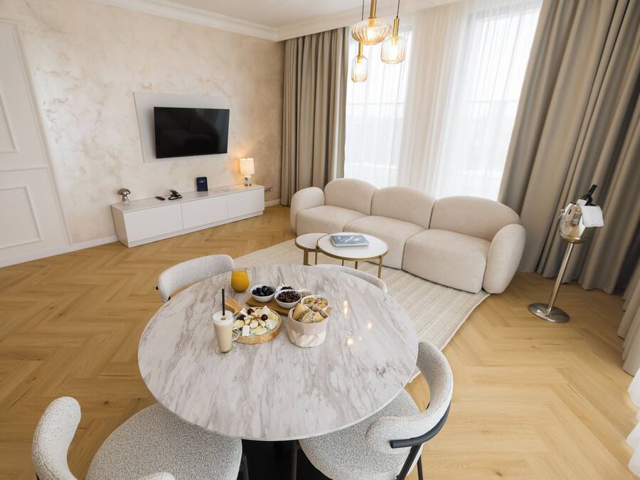 A modern living room with a marble dining table, a sofa, and a television mounted on the wall.