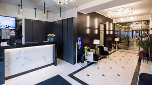 A modern hotel lobby with a marble reception desk, black and white decor, and a chandelier. - Le Blanc Cotroceni hotel (Bucharest)