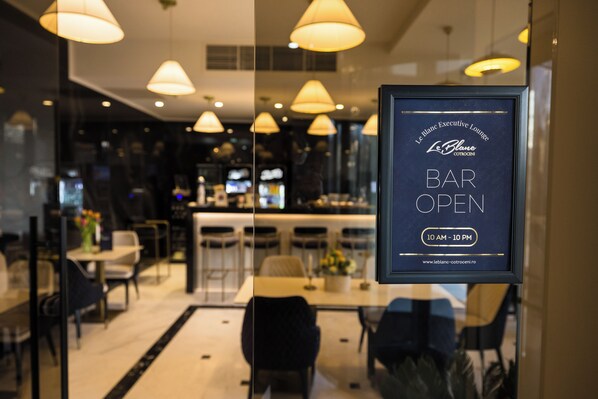 A bar sign with "LeBlanc Executive Lounge" and "BAR OPEN 10 AM - 10 PM" in a modern interior with pendant lighting. - Le Blanc Cotroceni hotel (Bucharest)