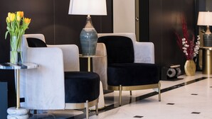 A modern lobby with two armchairs, a side table with a lamp, and a vase of yellow tulips. - Le Blanc Cotroceni hotel (Bucharest)