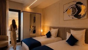 A hotel room with two beds, a sitting area, a large window, and a painting on the wall. - Le Blanc Cotroceni hotel (Bucharest)