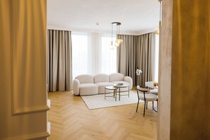 A modern living room with a sofa, a coffee table, and a dining area with a chair and table. - Le Blanc Cotroceni hotel (Bucharest)
