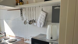 Una cocina equipada con microondas, hervidor y estufa.