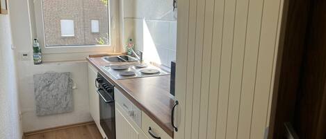 Una cocina funcional con ventana, un lavamanos y una estufa.