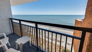 A balcony with a view of the beach and ocean.
