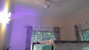 A room with a ceiling fan, a bed with a white headboard, and curtains on the windows. - Stan Lodge Babati (Babati)