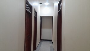 A narrow hallway with wooden doors and a tiled floor. - Stan Lodge Babati (Babati)
