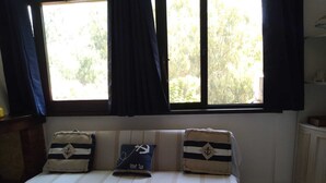 Une chambre avec un lit, une fenêtre avec des rideaux et une vue sur les arbres à l’extérieur.