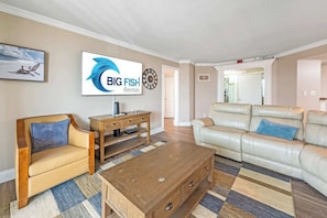 Un salon comprenant un canapé, une table basse en bois, un téléviseur et une enseigne indiquant « BIG FISH Rentals ».