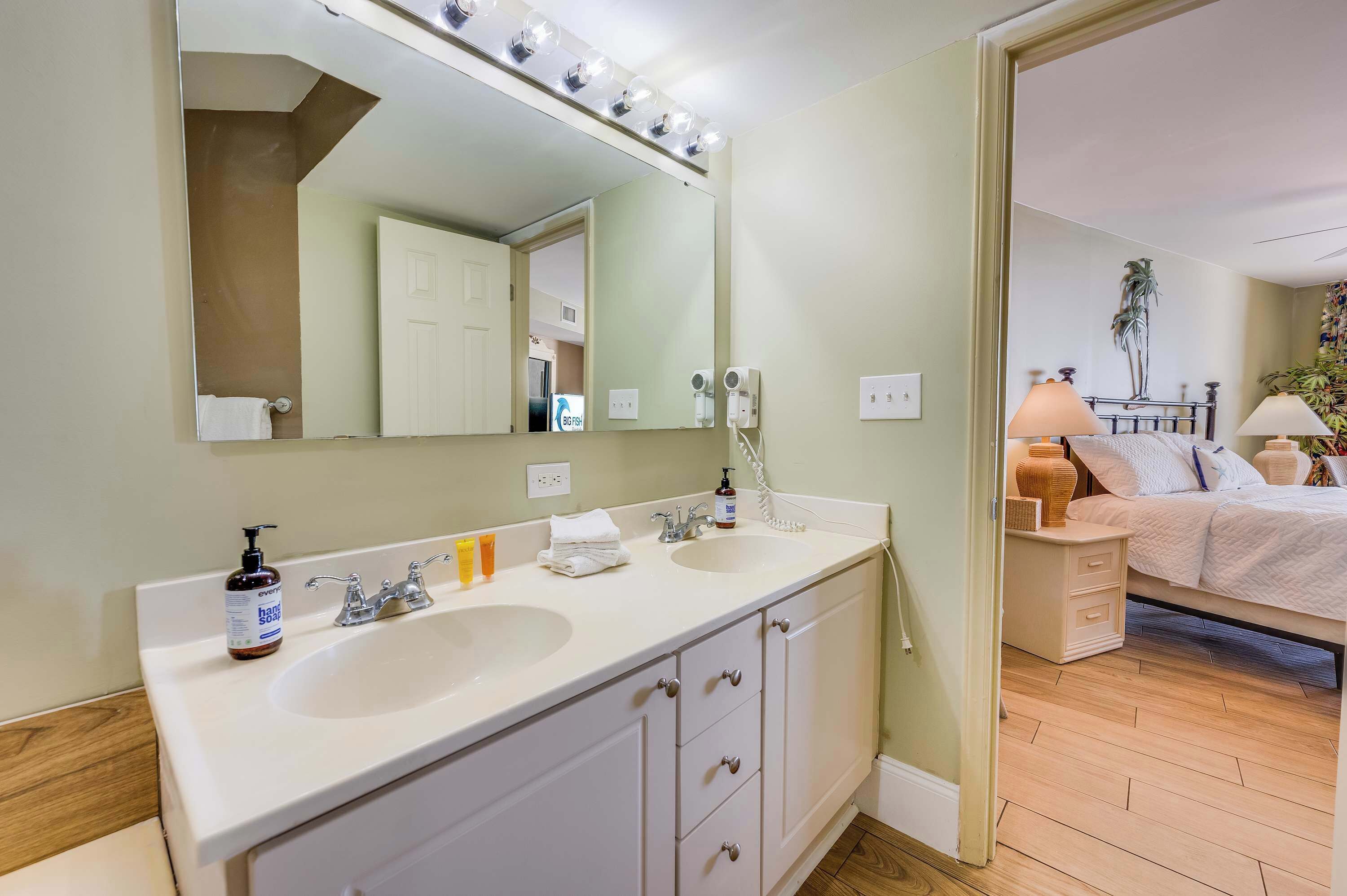 A bathroom with two sinks, a large mirror, and a vanity with drawers.