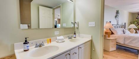 A bathroom with two sinks, a large mirror, and a vanity with drawers.