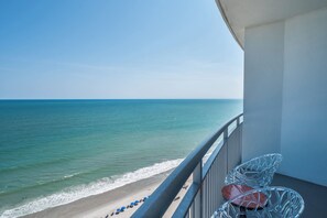 A balcony with a view of the beach and ocean.