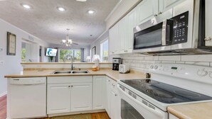 A modern kitchen with white cabinets, a microwave, an oven, and a dishwasher. - NEW! Large 2BR| River Oaks Golf | Pools | Hot Tubs (Myrtle Beach)