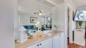 A kitchen with white cabinets, a wooden countertop, a ceiling fan, and a television on the wall. - NEW! Large 2BR| River Oaks Golf | Pools | Hot Tubs (Myrtle Beach)