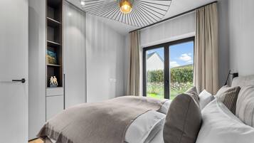 Una camera da letto moderna con un letto grande, un armadio e vista su un giardino tramite una porta scorrevole.