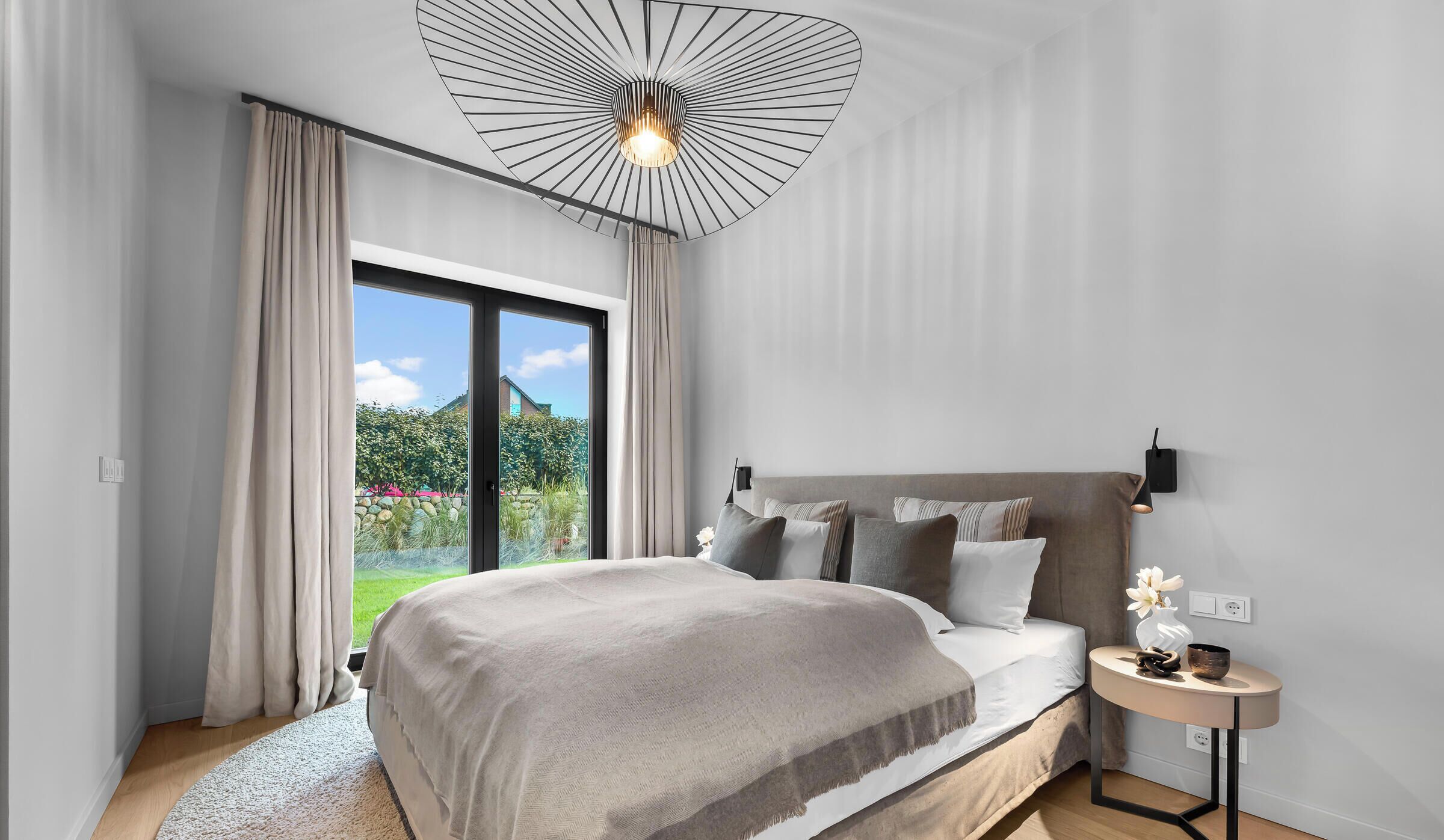 Una camera da letto moderna con un letto grande, un tavolino rotondo e vista sul verde circostante.