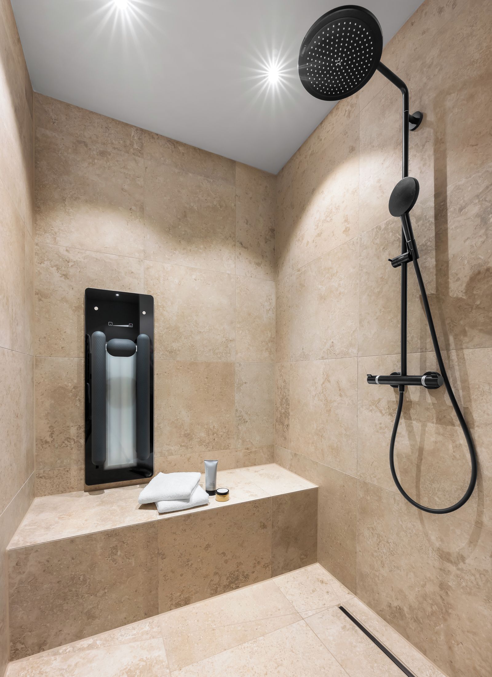 Un baño moderno con ducha integrada, un banco y un perchero para toallas.