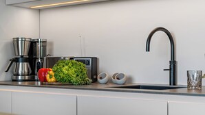 Une cuisine moderne équipée d’une machine à café en acier inoxydable, d’un grille-pain et d’un évier avec un robinet élégant.