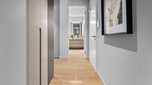Un couloir moderne avec un plancher en bois, des murs blancs et un tableau abstrait encadré sur le côté droit.