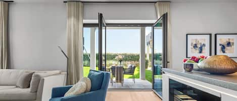 A modern living room with a sofa, a blue armchair, and a kitchen area with a built-in oven.