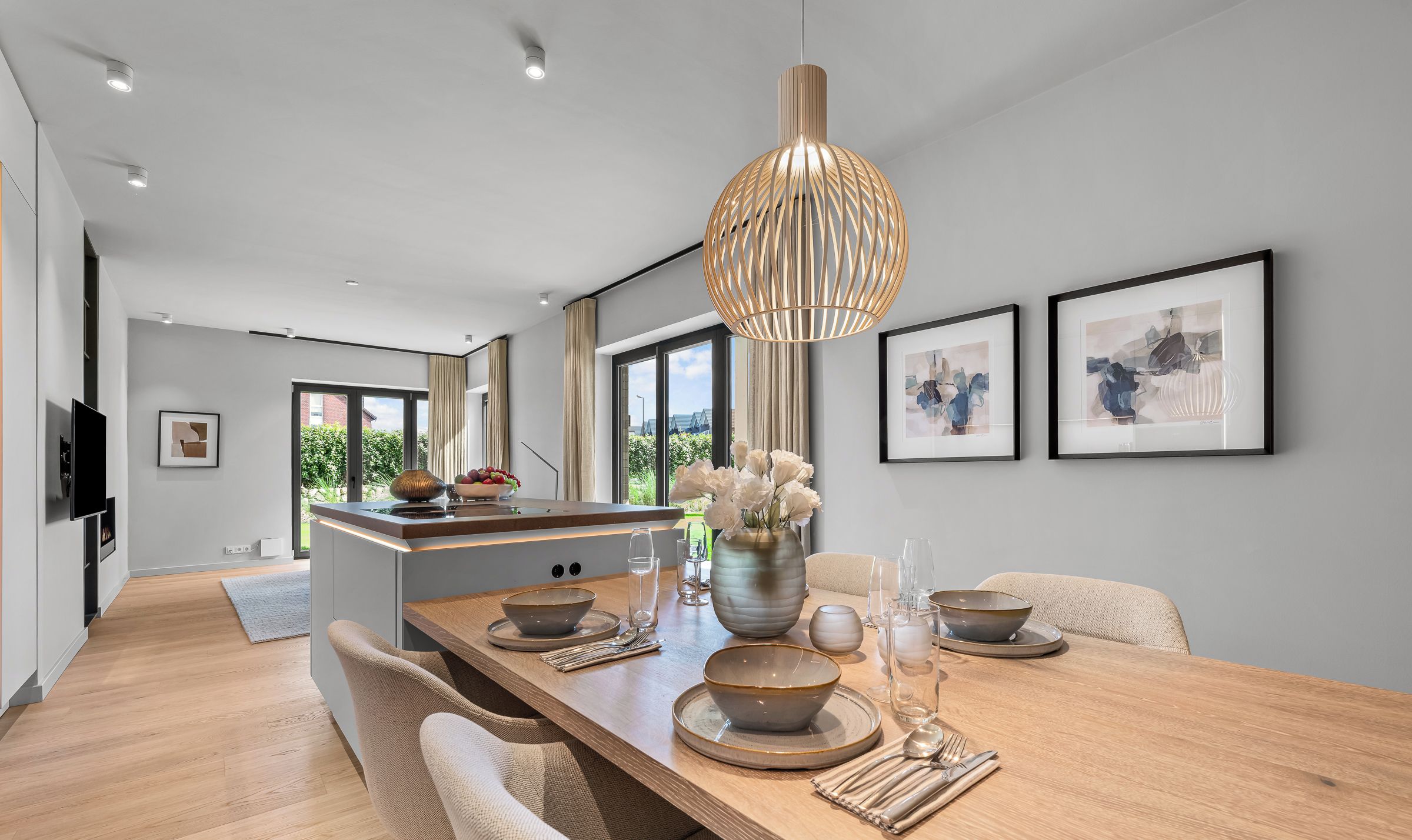 Een moderne keuken met een centraal eiland, hanglampen en kunstwerken in lijsten aan de wanden.