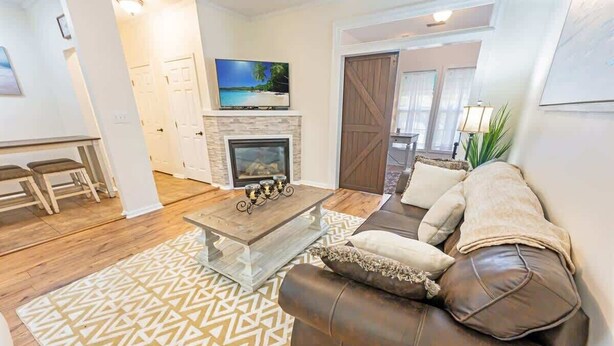 Un salon avec une cheminée, un canapé, une table basse et un tapis à motifs.