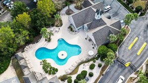 Vue aérienne d’un quartier résidentiel avec une piscine, une allée et un parking.