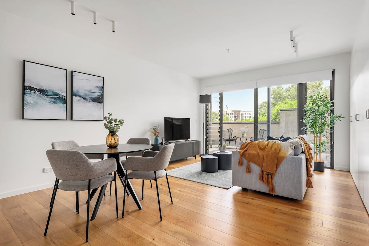 A modern living room with a dining area, large windows, and a view of the outdoors.